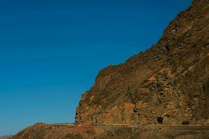 a road going through a canyon with a blue sky photo