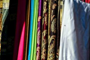 colorful fabrics hanging on a rack in a market photo