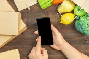 en línea comida compras concepto. manos con teléfono. foto