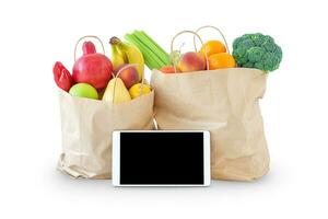 Shopping bags with fruit and vegetables and tablet screen photo