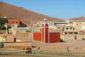 a red church in the desert with a hill in the background photo