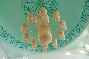 a chandelier in a mosque with a green ceiling photo