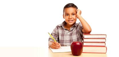 contento joven Hispano colegio chico a escritorio con libros y manzana aislado en un blanco antecedentes. foto
