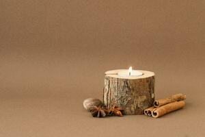 Ecological candle with cinnamon on the brown background photo