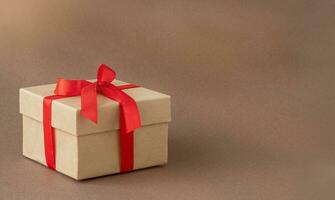 Holiday gift box with red ribbon on the brown background photo