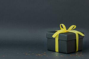 Black gift box with yellow ribbon photo