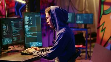 Portrait of asian hacker building spyware software designed to gather information from users computers without their knowledge. Man doing cybercriminal activities in rundown hideout video