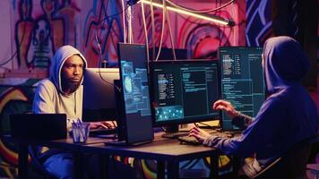 Hackers devising plan together, coding malware designed to exploit network backdoors, bypassing security measures such as logins and password protections in graffiti painted bunker video