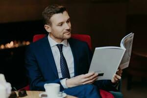 Serene executive reading a magazine, enjoying a coffee break in an elegant setting with ambient lighting photo