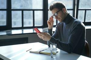 Man in glasses engrossed in smartphone, a moment of quiet reflection photo