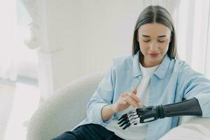 Content woman with bionic hand gently touching her forearm, showcasing the blend of humanity and technology photo