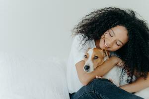 Serene woman with curly hair lovingly embracing her dog, sharing a peaceful moment photo