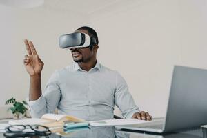 Man in VR headset gesturing, exploring virtual reality at his desk photo