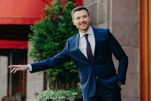 Cheerful businessman hailing a cab in a vibrant city setting, exuding confidence and style photo