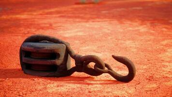 A rusty metal hook on a vibrant red dirt road photo