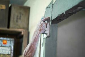 Closeup hands of builder holding mortar pan and plastering walls with cement in construction site. photo