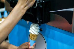 Closeup hand of seller hold and making soft ice cream by machine for customer photo