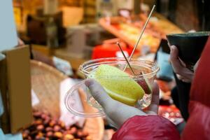 Closeup hands of tourist holding piece of Japanese pear and apple in a plastic cup on retail store background. photo