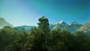 A house in the middle of a forest with mountains in the background photo