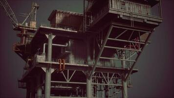 An oil rig towering over the ocean with a crane on top photo