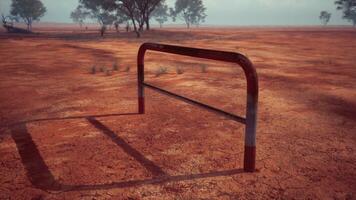 un rústico rojo suciedad campo con un encantador cerca y arboles en el antecedentes foto