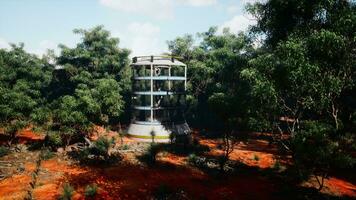 A futuristic glass greenhouse tower surrounded by lush forest photo