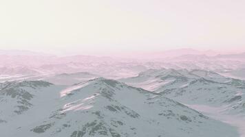 A snow-covered mountain range under a stunning pink sky photo