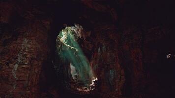 A mesmerizing green light shining through the entrance of a mystical cave photo