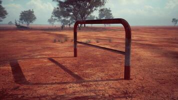 un rústico rojo suciedad campo con un encantador cerca y arboles en el antecedentes foto