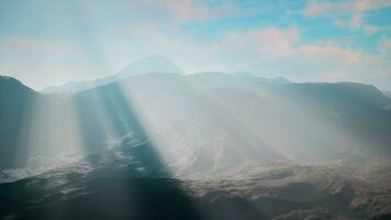 sunlight streaming through clouds over mountains photo