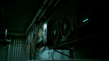 A dark concrete interior with a ceiling fan and multiple wires hanging from it photo