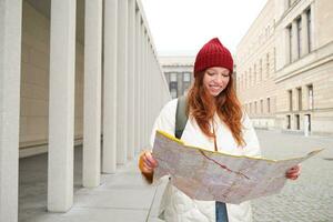 Redhead girl, tourist explores city, looks at paper map to find way for historical landmarks, woman on her trip around euope searches for sightseeing photo