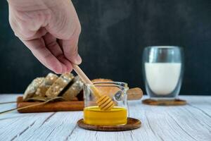 Male hand pouring honey With bread and milk for breakfast photo