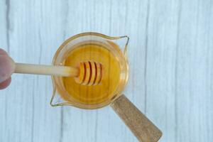 Male hand using a stick for stirring honey in a measuring cup. photo