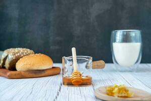 desayuno conjunto miel en un medición taza con un pan y Leche foto