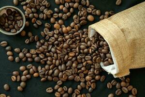 Coffee beans in refillable coffee capsules, coffee bags and around on a black background. photo