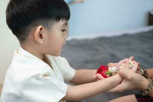 Little asian boy Giving a jasmine garland to mother On Thailand's National Mother's Day photo