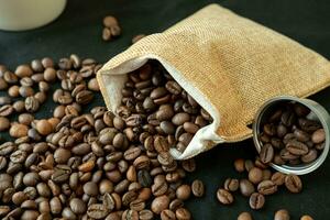 Coffee beans in refillable coffee capsules, coffee bags and around on a black background. photo