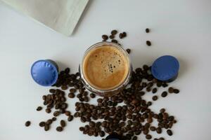 Coffee mug with crema with coffee capsule elements, coffee beans, on a white background. photo