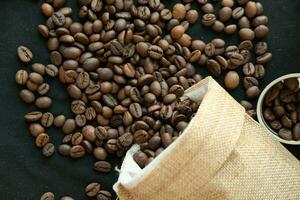 Coffee beans in refillable coffee capsules, coffee bags and around on a black background. photo