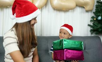 alegre Navidad 2024 concepto chico recibe un regalo desde su madre a Navidad foto