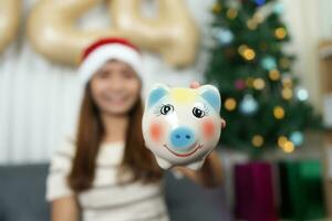 Merry Christmas 2024 concept Asian woman receives piggy bank in Christmas box photo