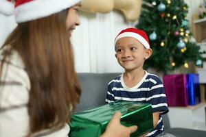 alegre Navidad 2024 concepto chico recibe un regalo desde su madre a Navidad foto