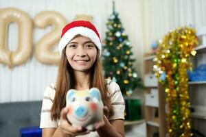 Merry Christmas 2024 concept Asian woman receives piggy bank in Christmas box photo