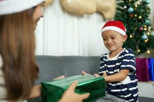 alegre Navidad 2024 concepto chico recibe un regalo desde su madre a Navidad foto