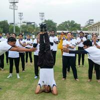 nuevo Delhi, India, junio 21, 2023 - grupo yoga ejercicio sesión para personas a yamuna Deportes complejo en Delhi en internacional yoga día, grande grupo de adultos asistiendo yoga clase en Grillo estadio foto