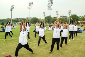 nuevo Delhi, India, junio 21, 2023 - grupo yoga ejercicio sesión para personas a yamuna Deportes complejo en Delhi en internacional yoga día, grande grupo de adultos asistiendo yoga clase en Grillo estadio foto