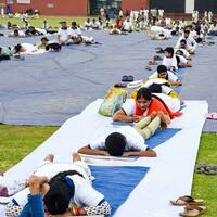 New Delhi, India, June 21, 2023 - Group Yoga exercise session for people at Yamuna Sports Complex in Delhi on International Yoga Day, Big group of adults attending yoga class in cricket stadium photo