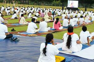 New Delhi, India, June 21, 2023 - Group Yoga exercise session for people at Yamuna Sports Complex in Delhi on International Yoga Day, Big group of adults attending yoga class in cricket stadium photo