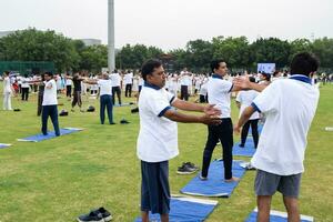 nuevo Delhi, India, junio 21, 2023 - grupo yoga ejercicio sesión para personas a yamuna Deportes complejo en Delhi en internacional yoga día, grande grupo de adultos asistiendo yoga clase en Grillo estadio foto